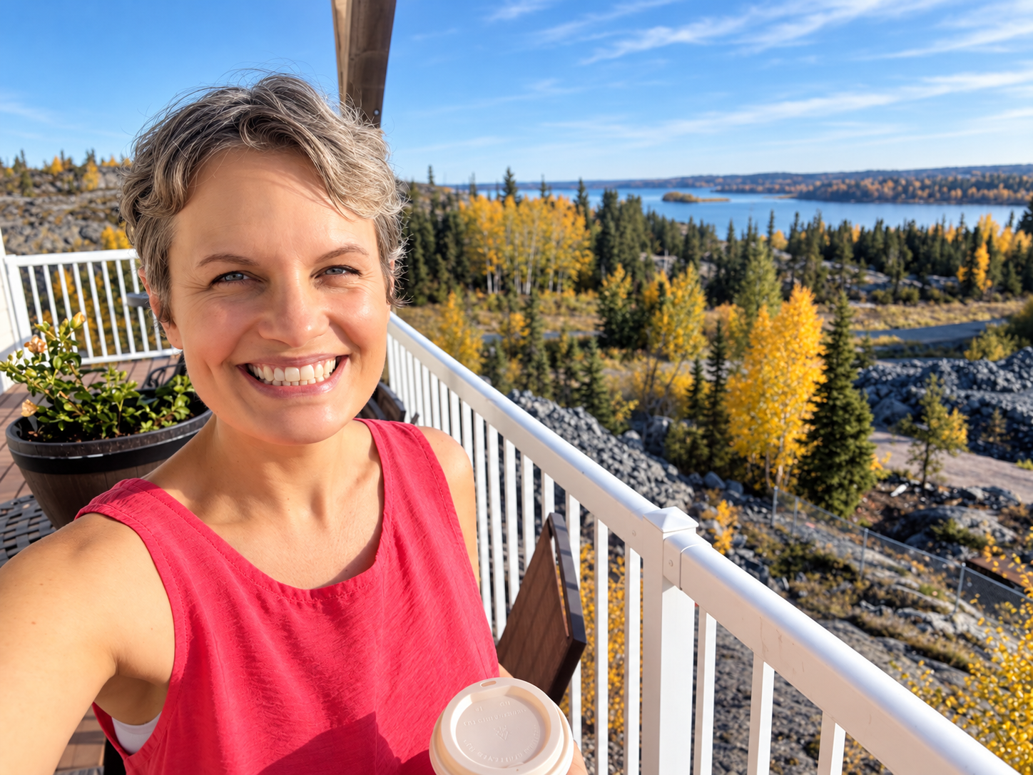 Rina smiling on a balcony overlooking a lake in autumn